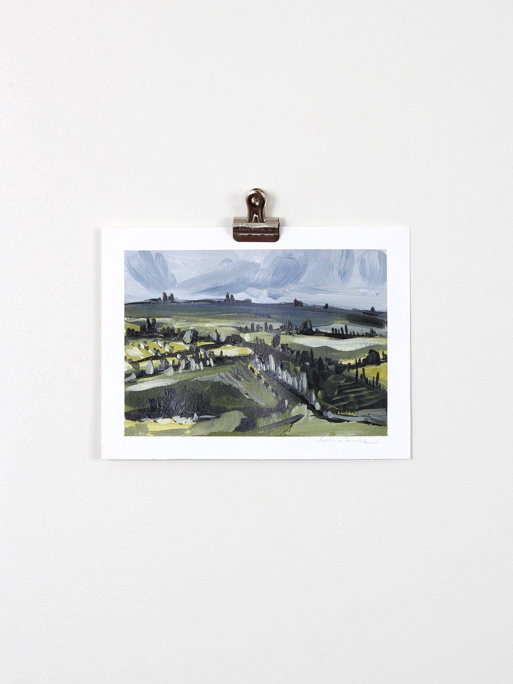 Landscape painting clipped to a white wall.
