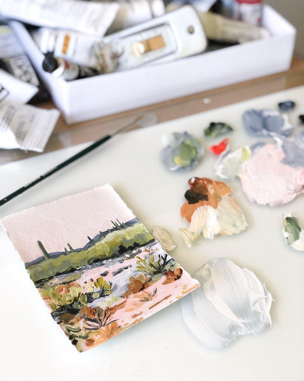 Painting supplies with a small landscape artwork.