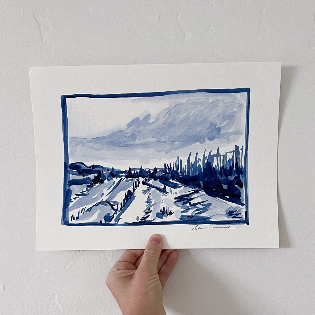 Ink painting of a landscape held by a hand.