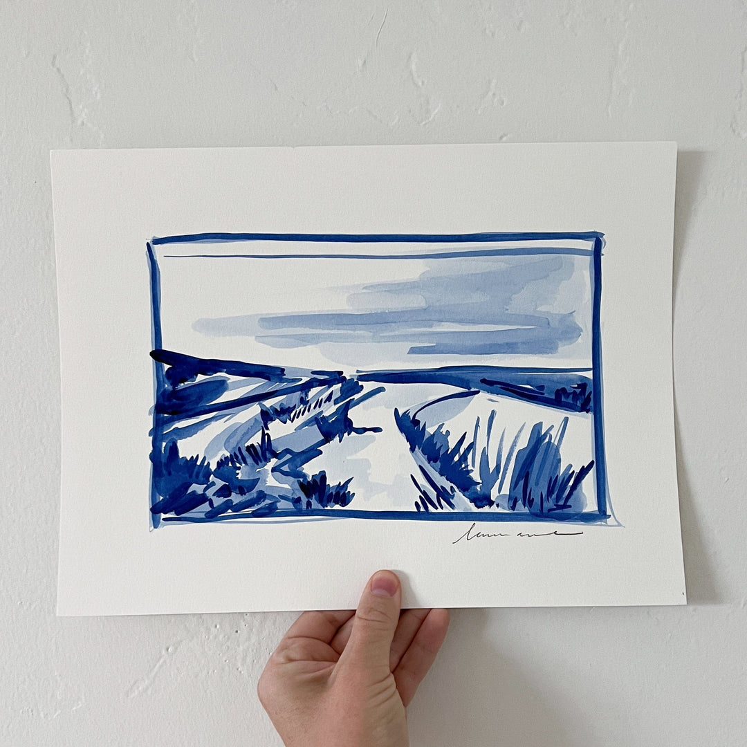 Blue ink landscape painting held by hand.