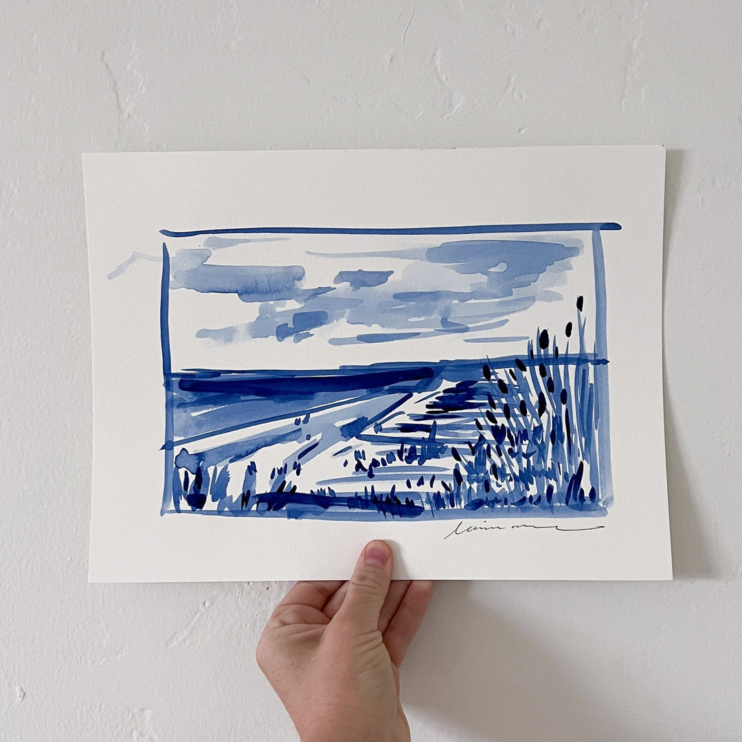 Blue watercolor landscape painting held by a hand.