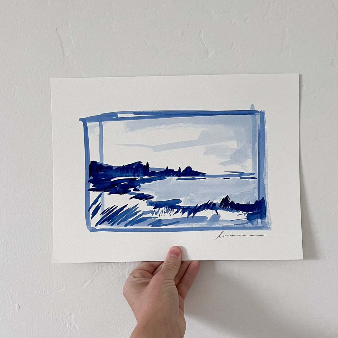 Hand holding a blue watercolor landscape painting.