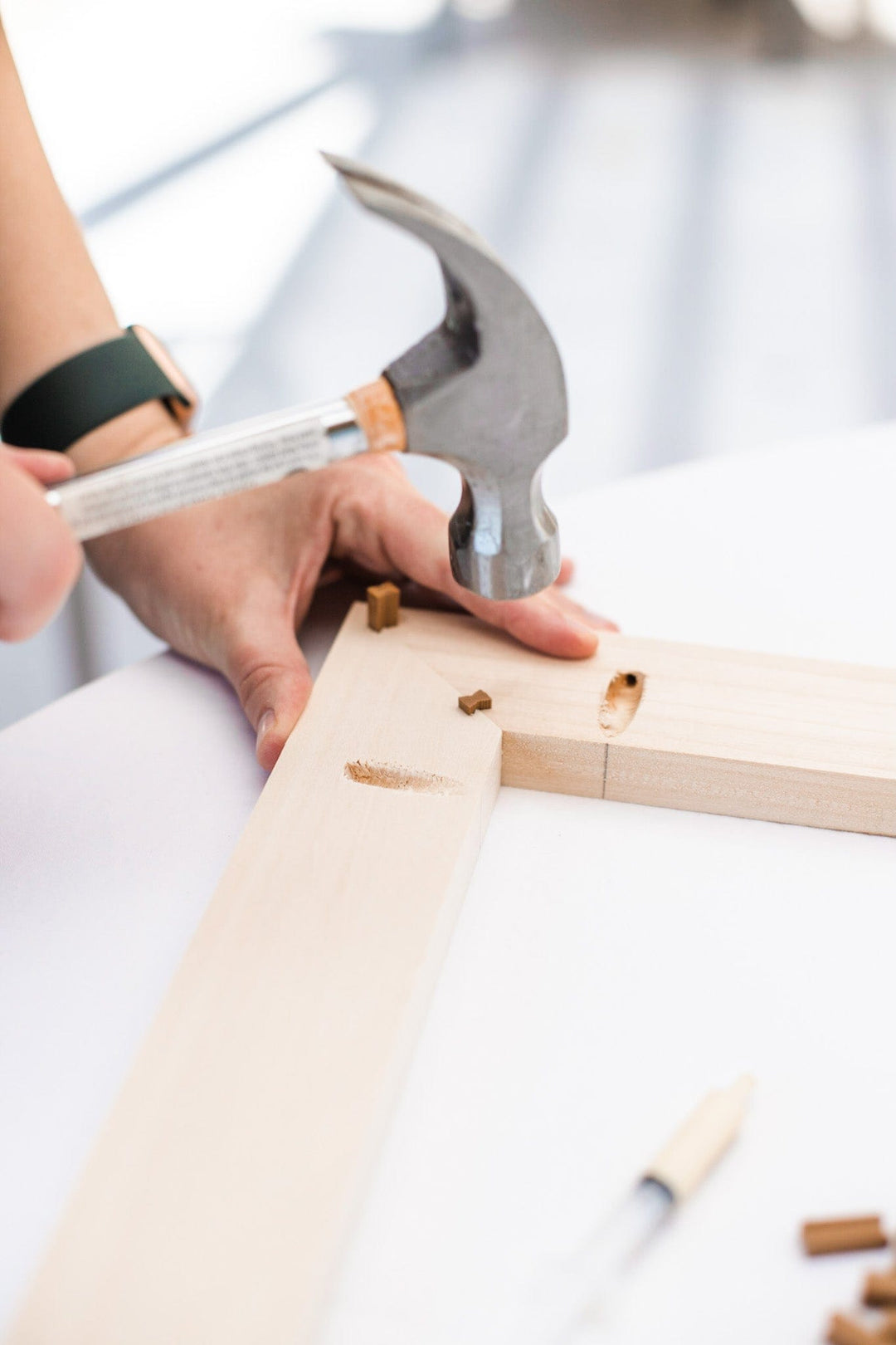 Person hammering a wooden frame.
