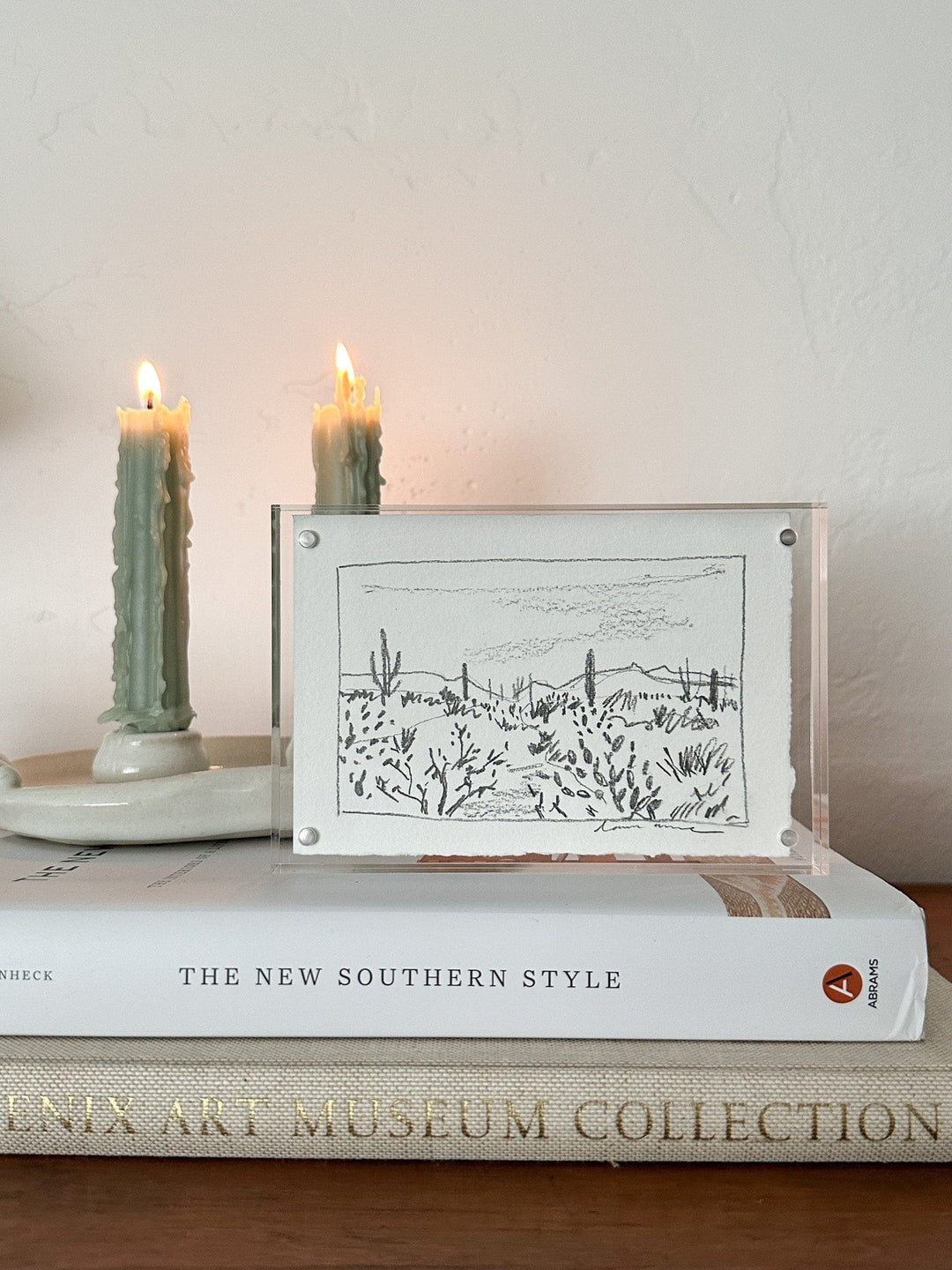 Drawing of desert scene between two candles.