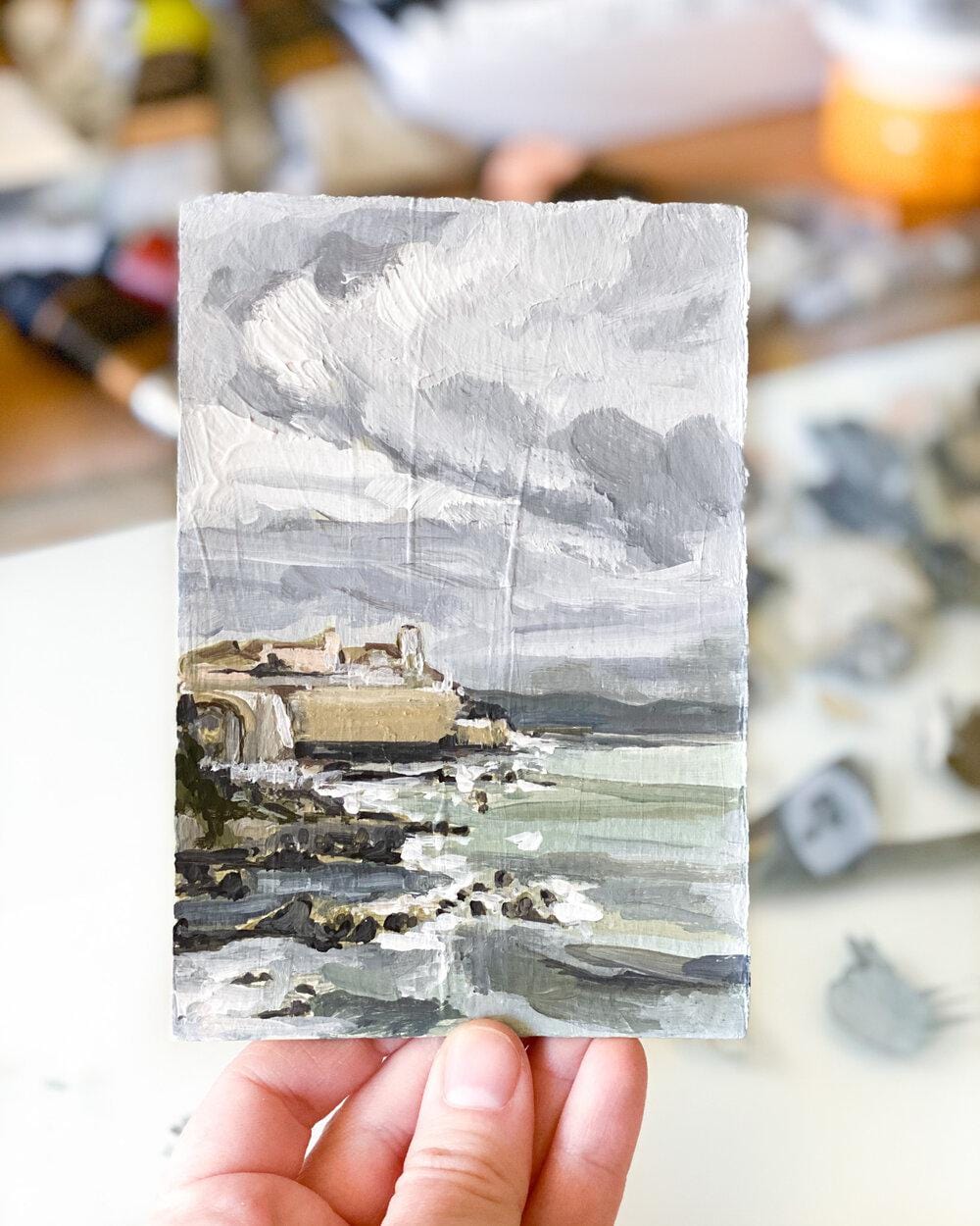 Miniature landscape painting of coast and cloudy sky.