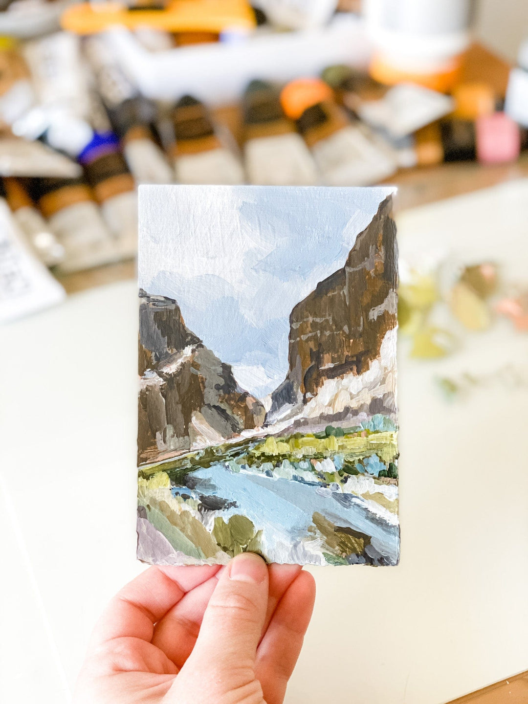 Painting of a mountain landscape held in hand.