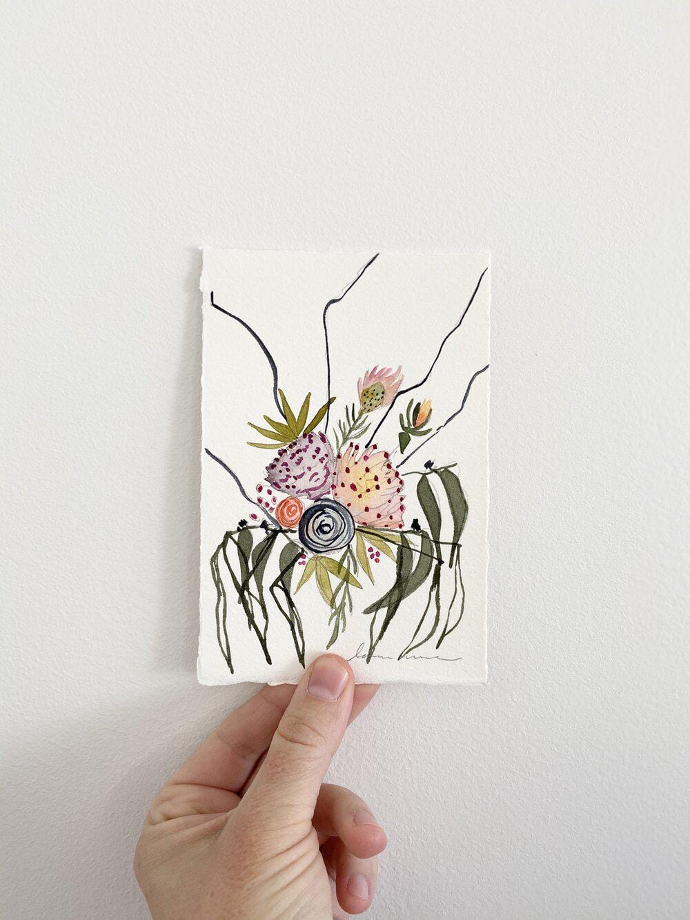 Hand holding watercolor floral art print.