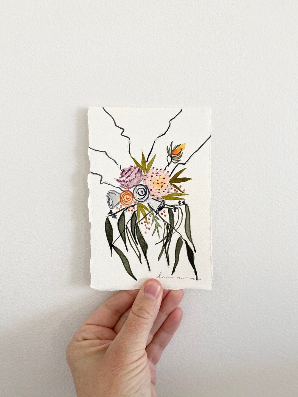 Hand holding floral watercolor painting.