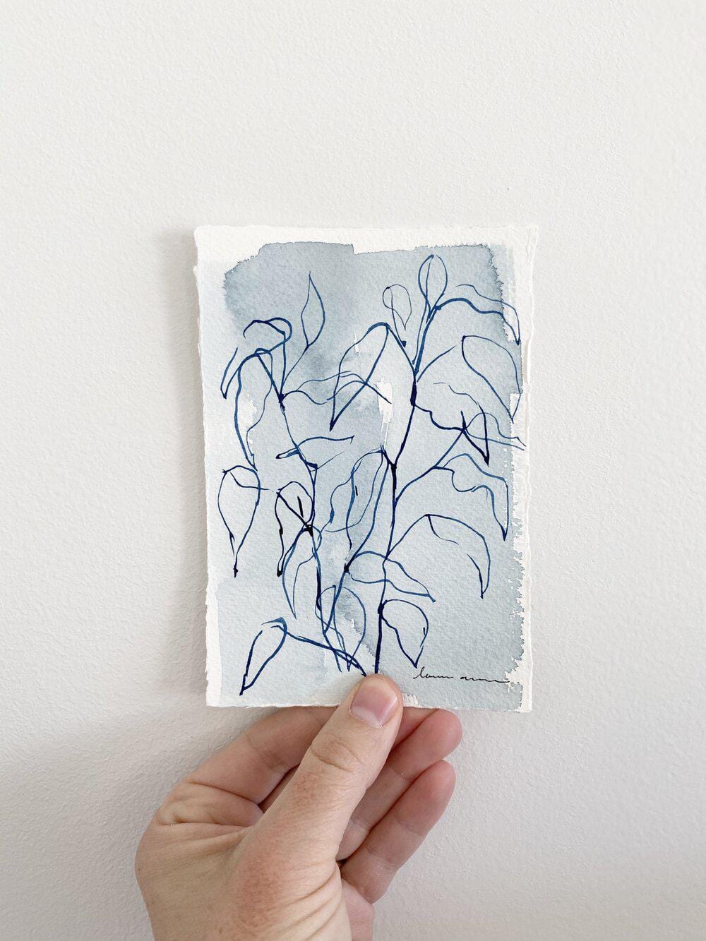 Hand holding a watercolor painting of a plant.