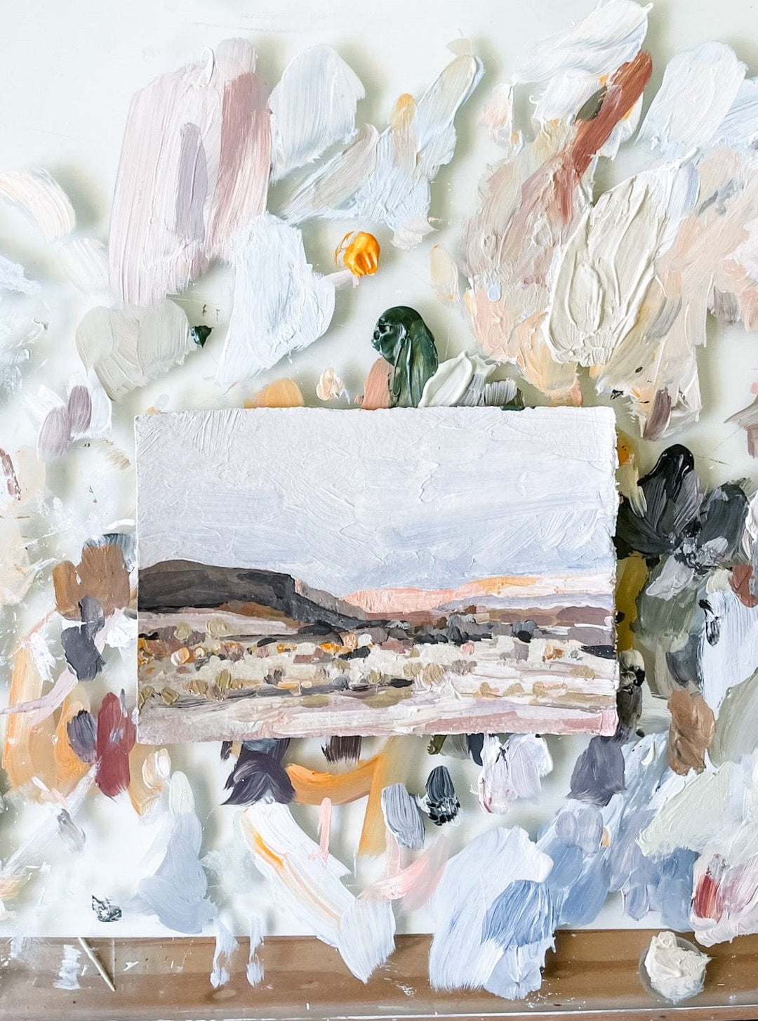 Landscape painting on a palette with paint splotches.