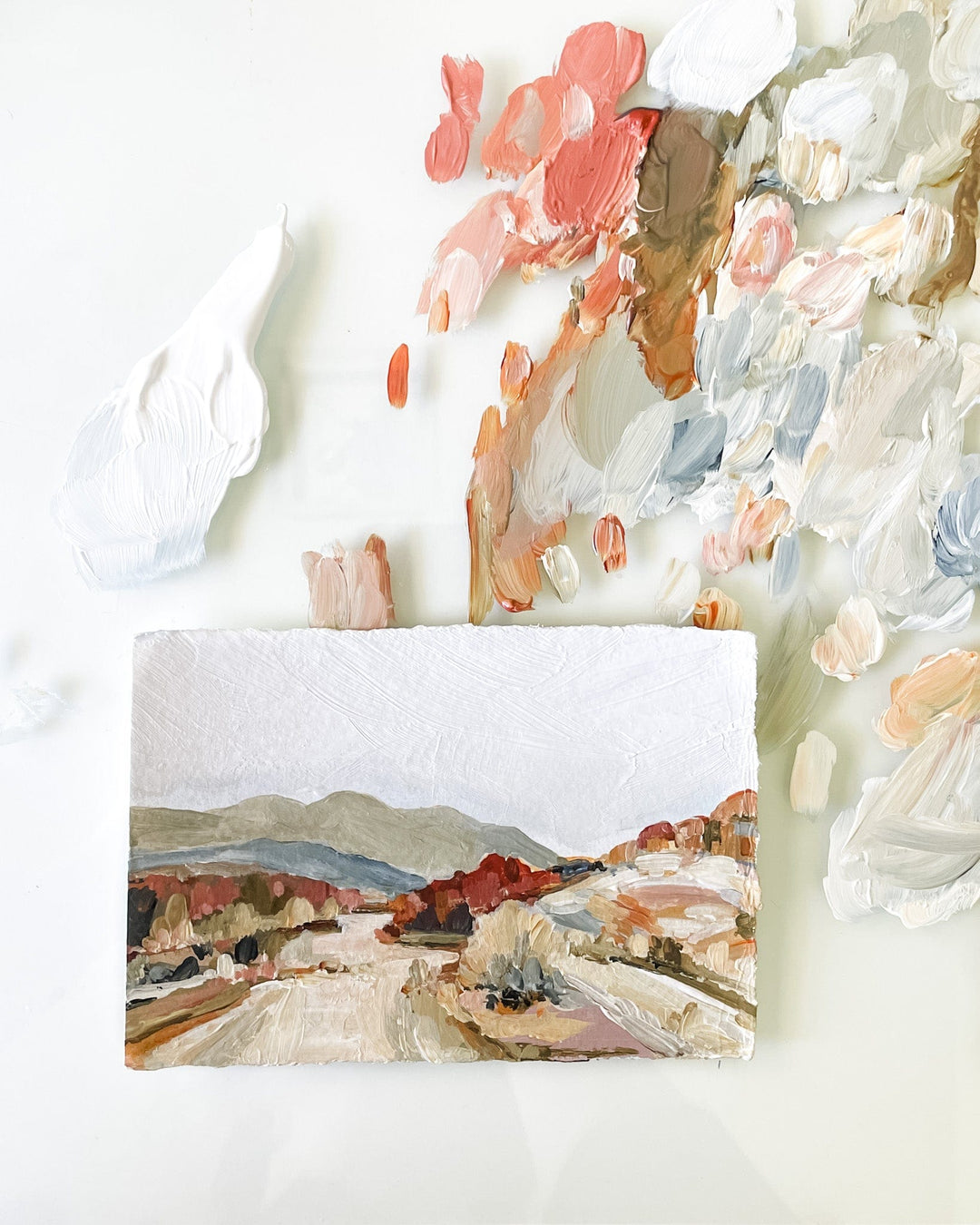 Landscape painting with paint splotches on white surface.