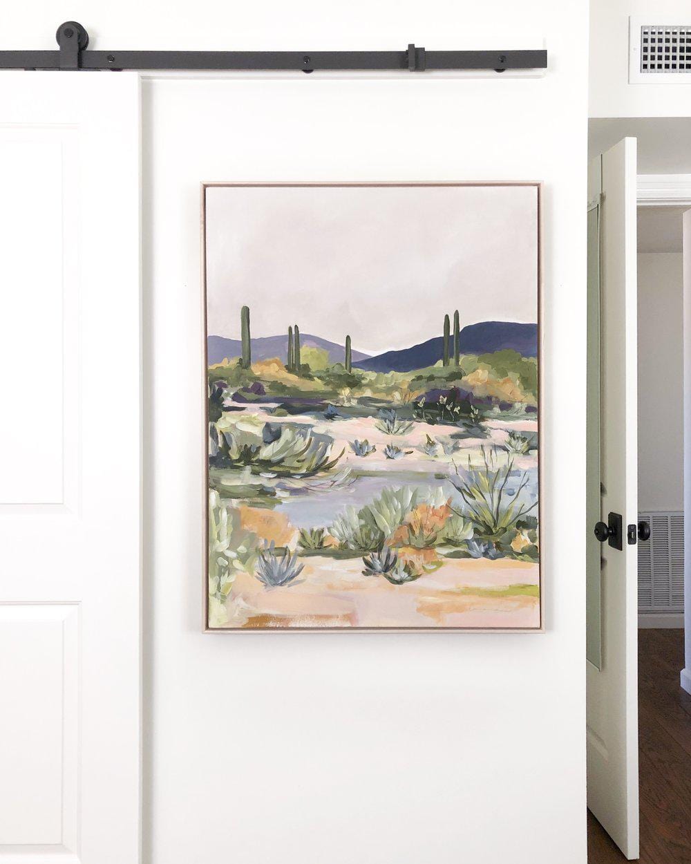Painting of desert landscape on a white wall.