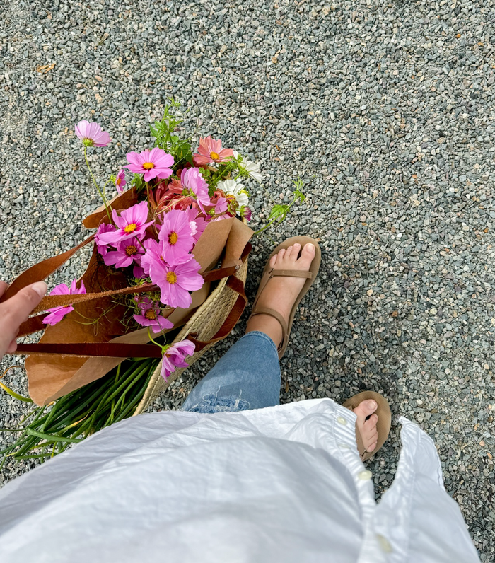 a woman carrying flowers in a market tote bag