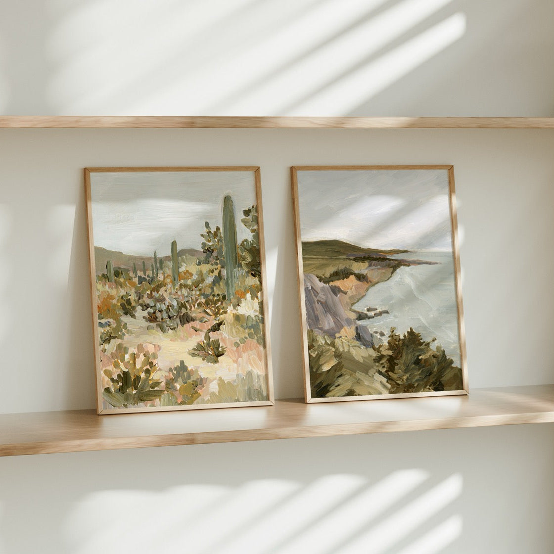 Two framed artworks on a shelf with a neutral background