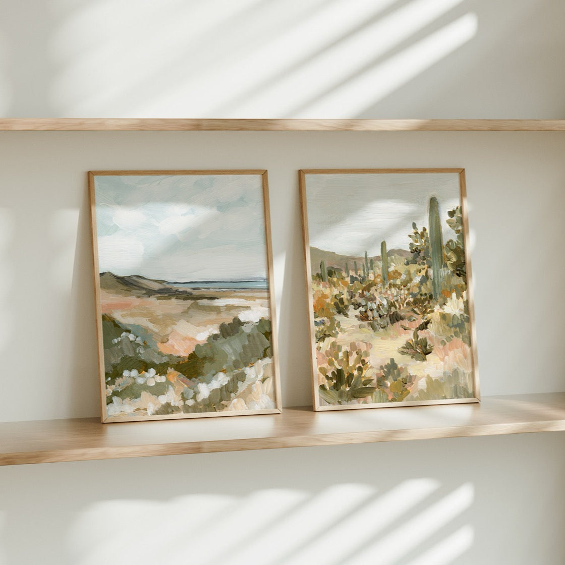 Two framed artworks on a shelf with a neutral background